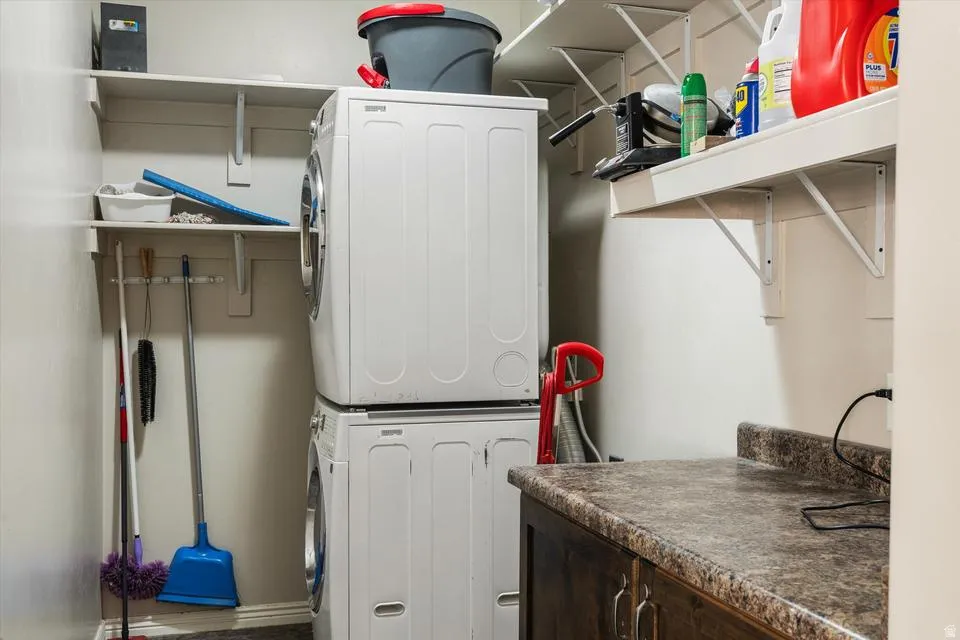 Stackable laundry appliances, built-in shelving, and a countertop with cabinetry