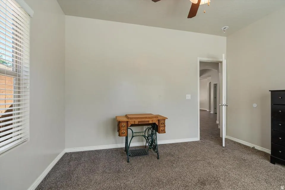 Carpeted room featuring a ceiling fan, window with blinds, and white trim