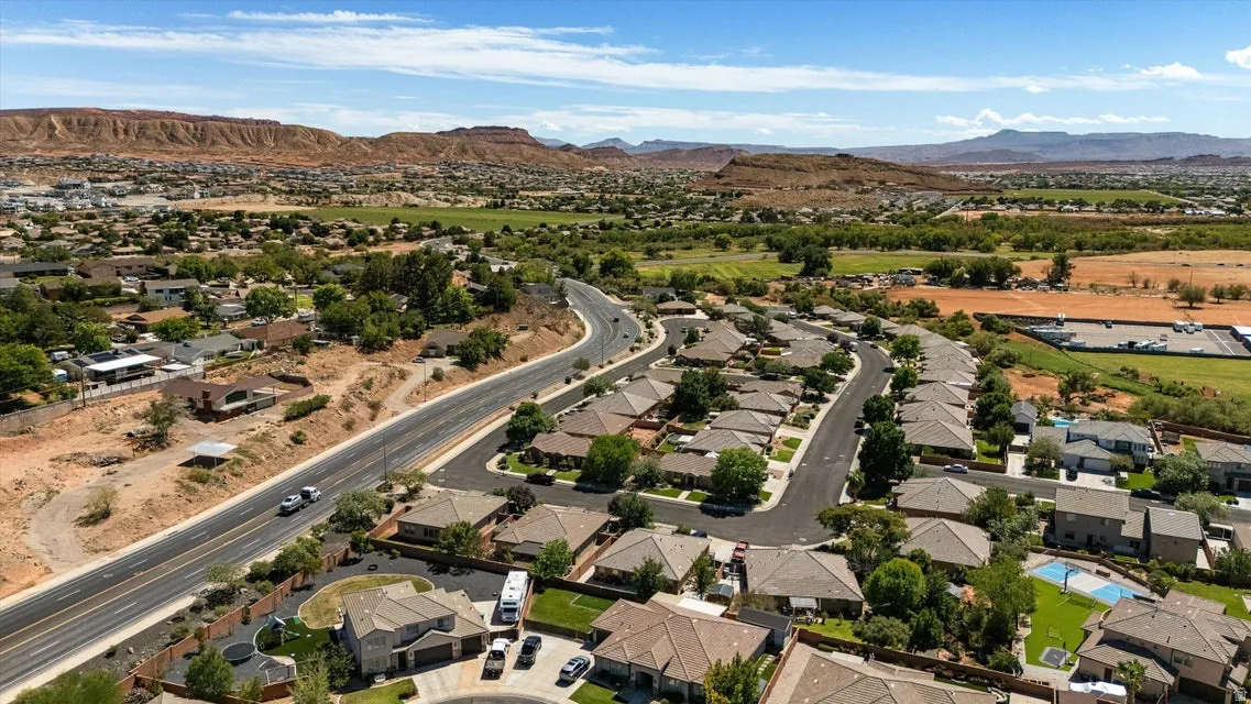Residential area with paved roads, mature trees, and a mountain backdrop