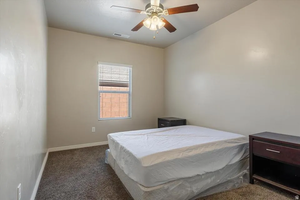 Carpet flooring, neutral painted walls, ceiling fan with light fixture, window with blinds