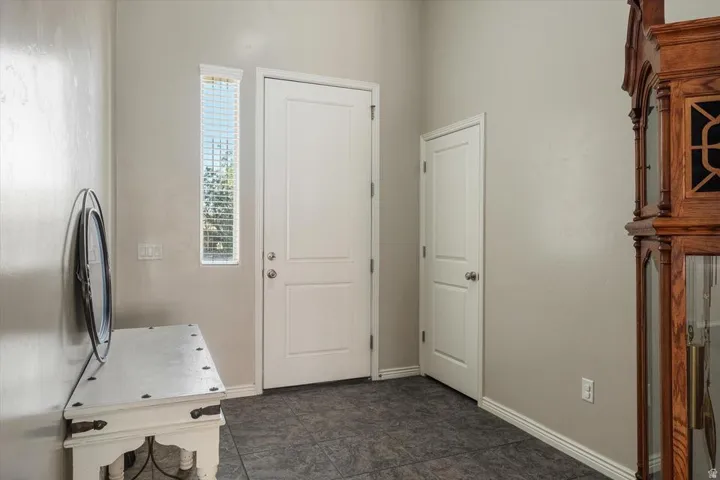 Entry area with tile flooring, a vertical window with blinds, and white interior doors