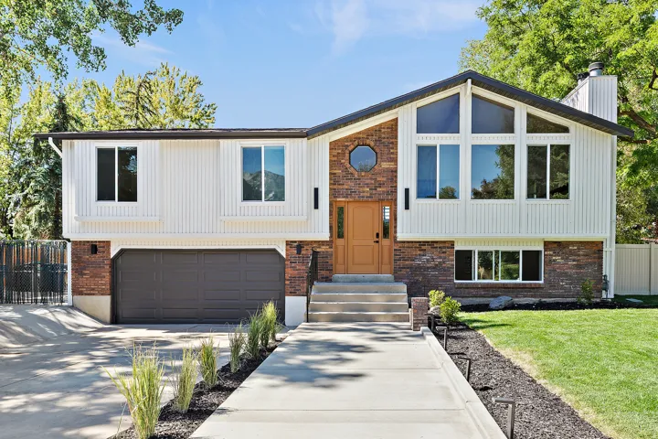 Split-level residence featuring a brick and vertical siding exterior, a prominent gable roofline, and an integrated two-car garage