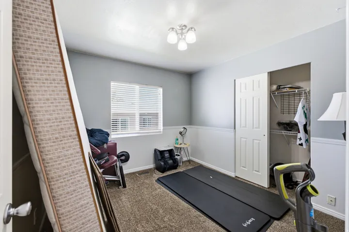 Carpeted room with a window featuring blinds, a ceiling-mounted light fixture, and a built-in closet with sliding doors