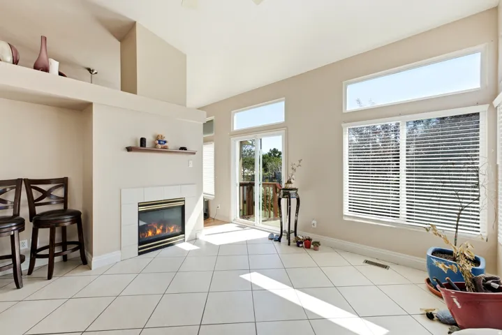 Tile flooring, fireplace with tile surround, sliding glass door, multiple large windows, and a built-in display shelf