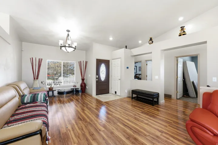 Wood-finish flooring, vaulted ceilings, recessed lighting, and a dark wood-paneled entry door with an oval glass insert