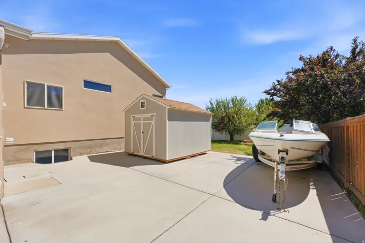 Paved side yard offering substantial hardscaping, a detached storage shed, and a wooden privacy fence