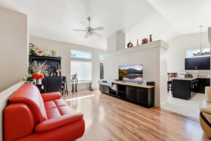 Vaulted ceiling with a ceiling fan, wood-finish flooring, half wall, and a built-in media cabinet
