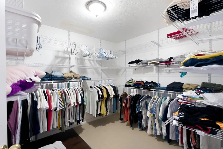 Walk-in closet featuring an overhead light fixture, light-colored walls, and multiple levels of wire shelving and hanging rods