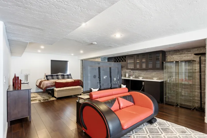 Dark wood-finish flooring, recessed lighting, and a stone-clad accent wall create a distinctive ambiance
