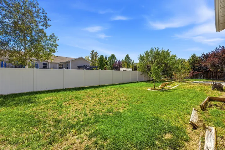 Expansive green lawn with a white privacy fence and mature trees