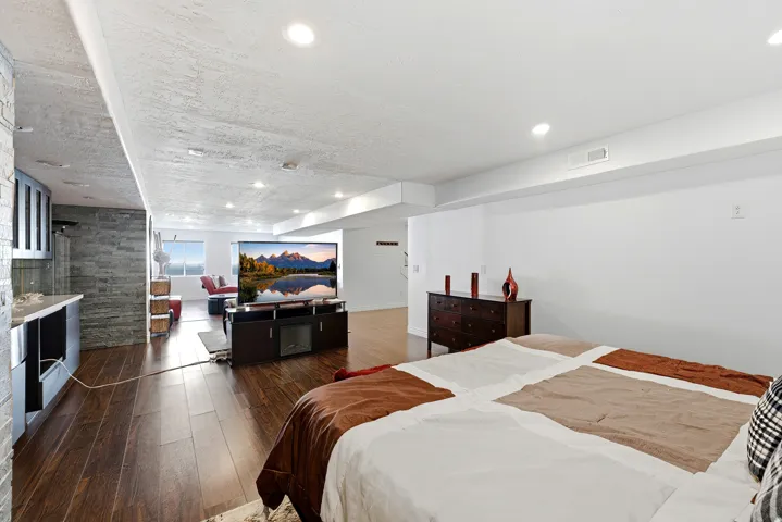 Recessed lighting, wood-finish flooring, stone-finish accent wall, built-in cabinetry, and white walls