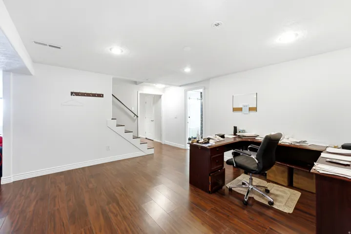Spacious room featuring wood-finish flooring, white walls, and recessed lighting