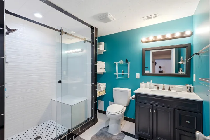 Glass-enclosed shower with textured white tile and built-in bench