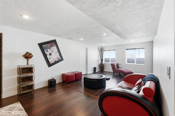 Recessed lighting illuminates the wood-finish flooring and white walls