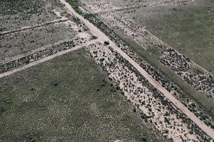 Expansive arid land featuring natural vegetation and a visible dirt road