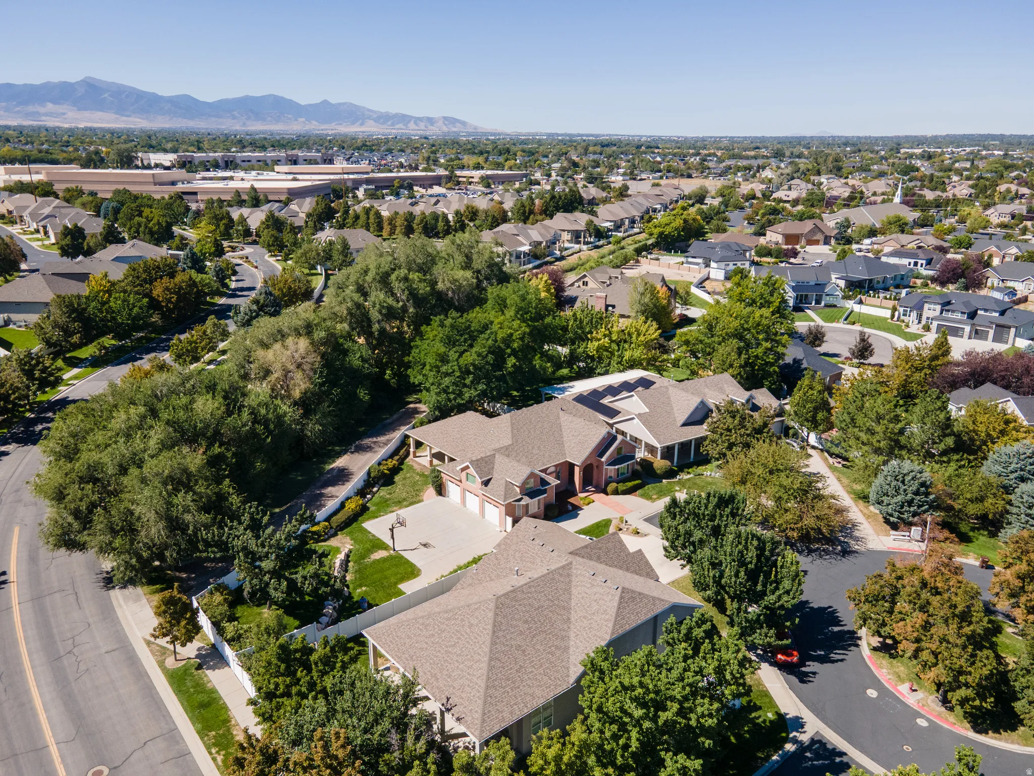 Expansive property featuring a multi-car driveway, mature landscaping, and a fenced perimeter