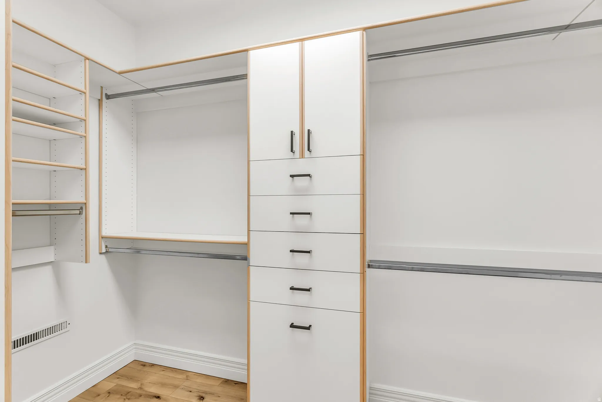 Custom closet system with integrated shelving, multiple hanging rods, built-in drawers, and overhead cabinetry