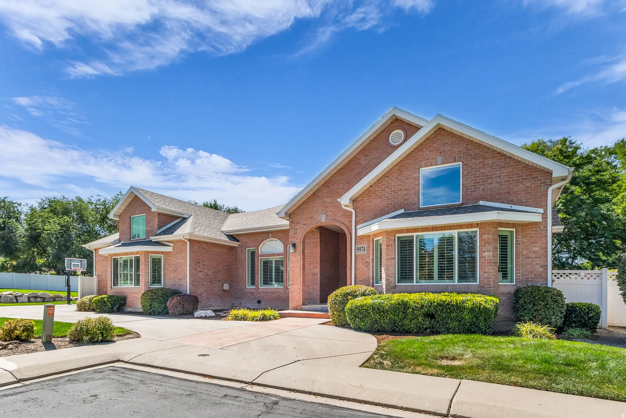 Brick exterior with a gabled roofline, multiple windows with shutters, and a paved driveway
