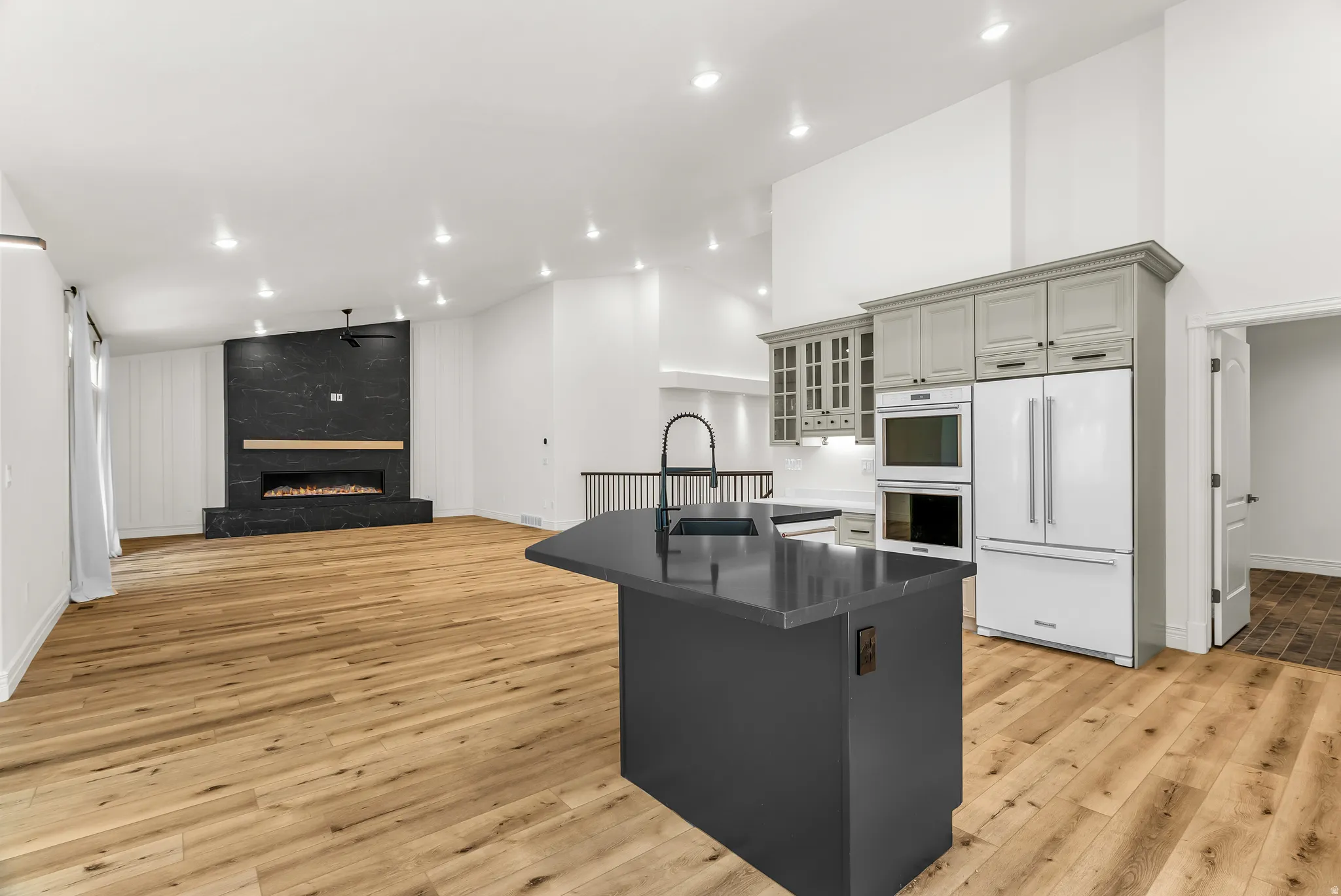 Open-concept living space with vaulted ceilings, wood-finish flooring, and recessed lighting
