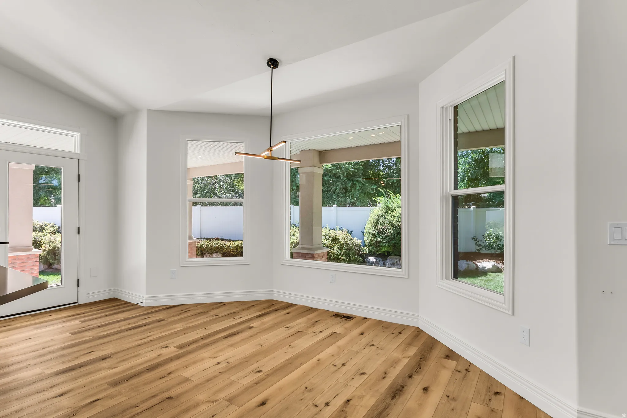 Wood-finish flooring, white walls, and a contemporary linear chandelier define this space