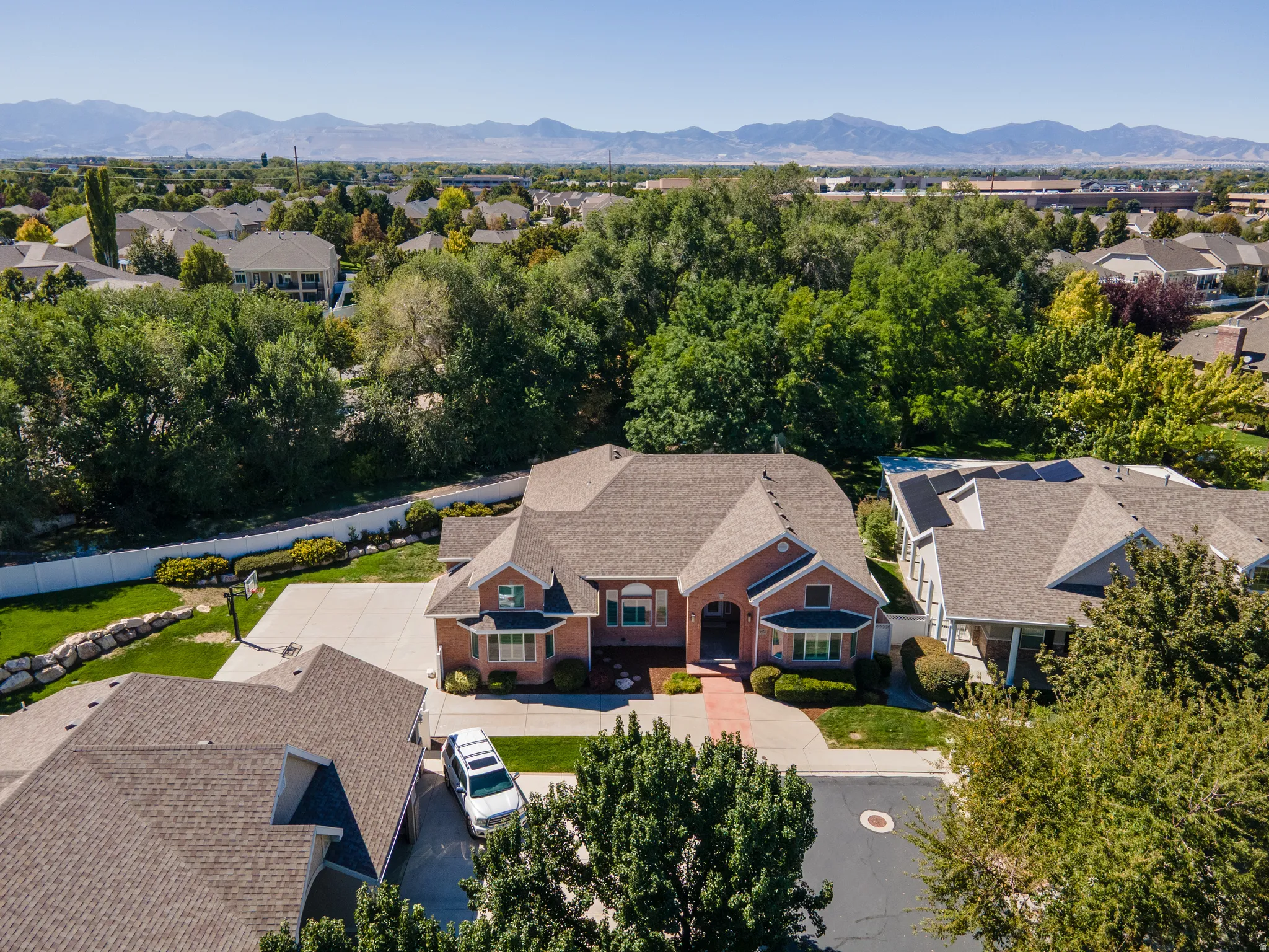 Brick exterior with a multi-gabled roofline, concrete driveway, and mature landscaping