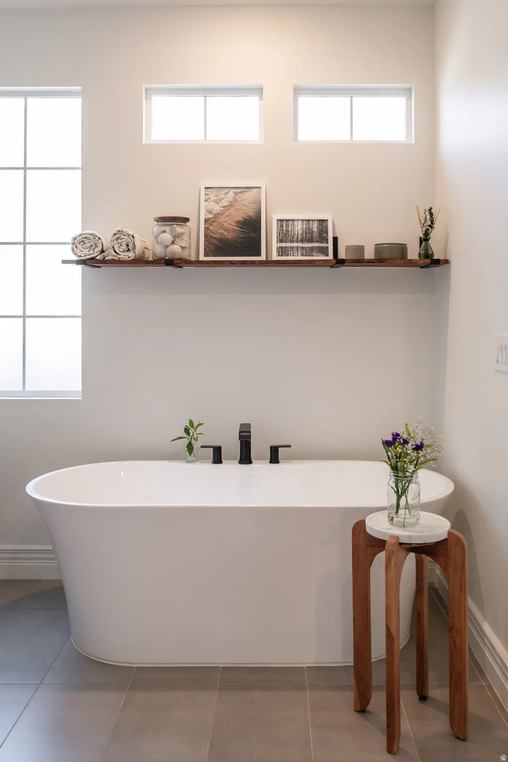 Freestanding bathtub with matte black fixtures, set on large format floor tiles