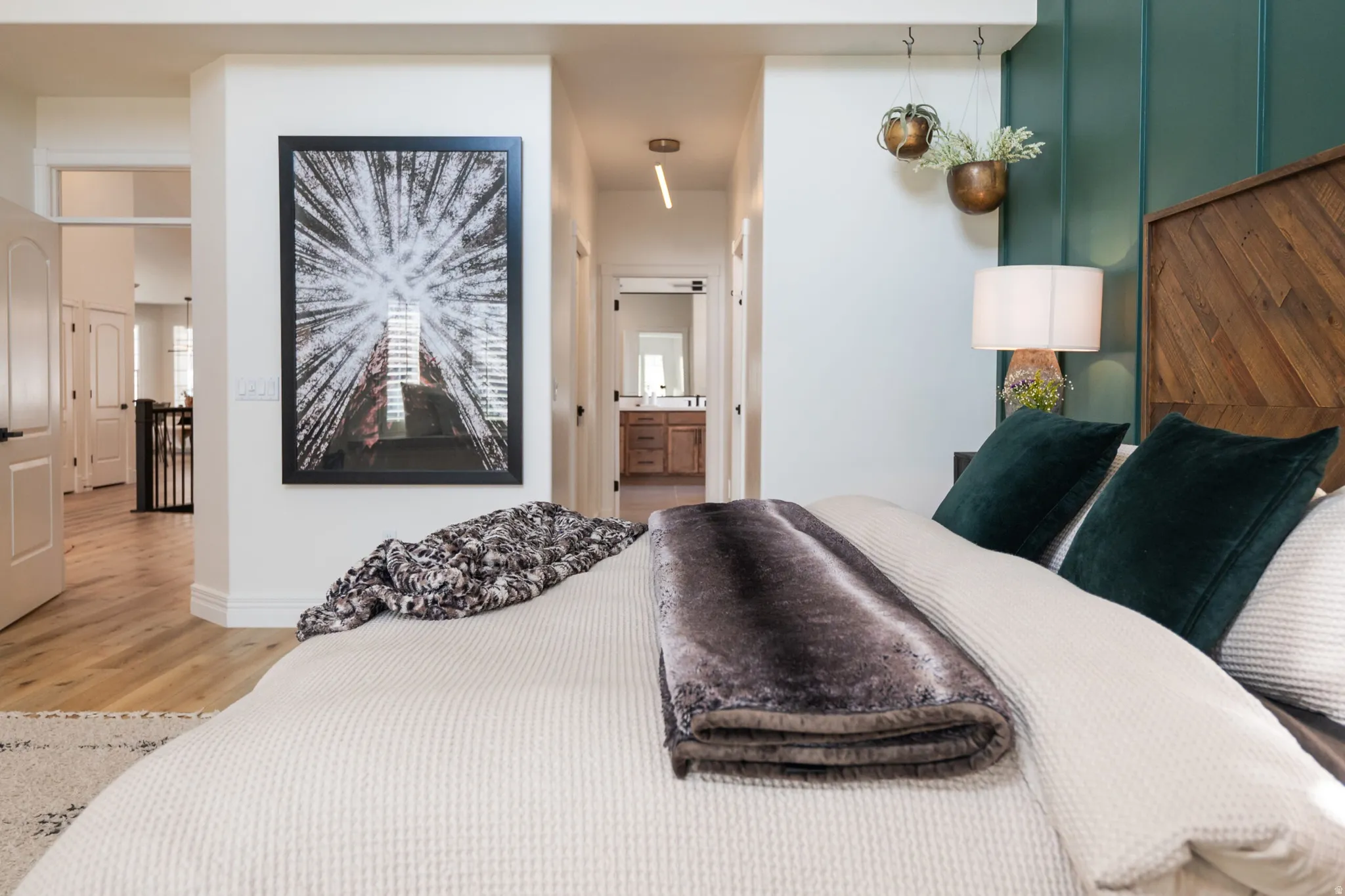 Wood-finish flooring throughout, a decorative wood-panel accent wall, and a wood chevron-pattern headboard