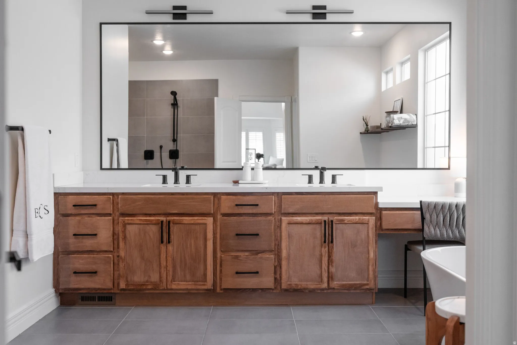 Dual vanity with wood-finish cabinetry, white countertop, and integrated makeup area