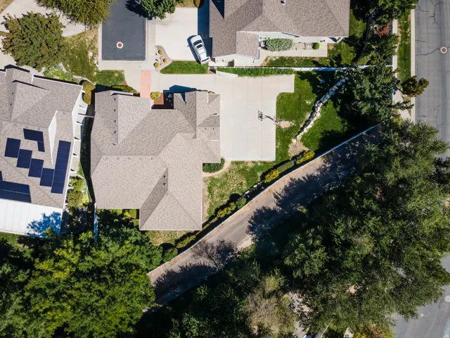 Asphalt shingle roofing, concrete driveway, manicured lawn, perimeter fencing, and mature trees