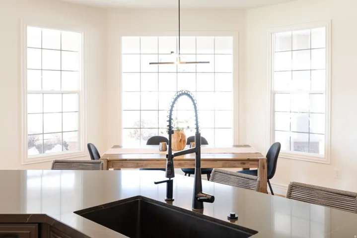 Large kitchen island with a dark sink and matte black faucet