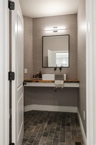 Powder room featuring a rectangular vessel sink, wood-finish countertop, wall-mounted faucet, and rectangular mirror with a black frame