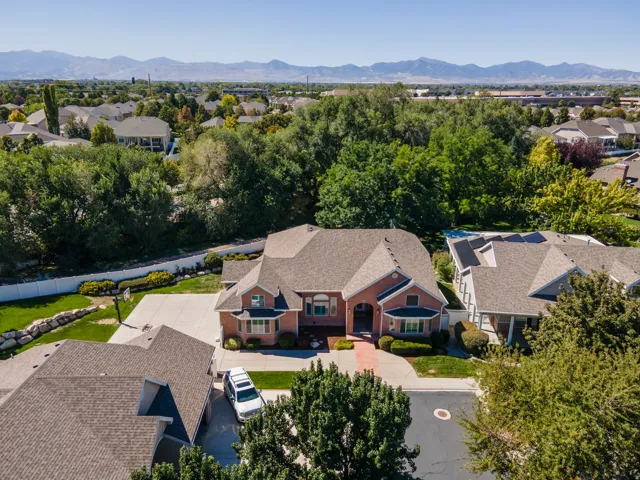 Brick exterior with a multi-gabled roofline, concrete driveway, and mature landscaping