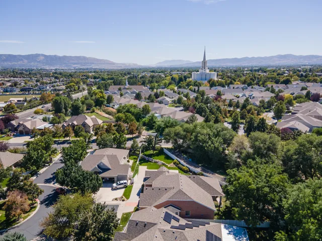 Residential neighborhood with mature trees, mountain backdrop, and distant architectural spire