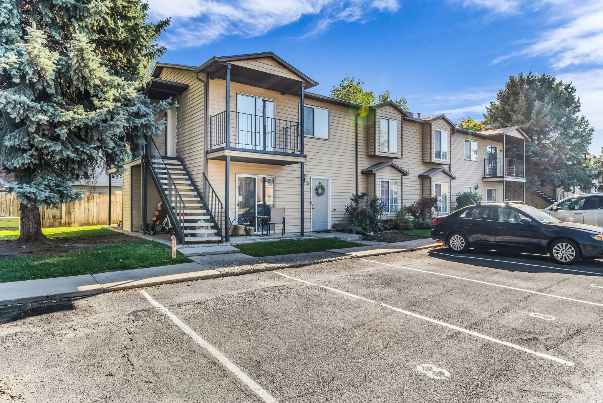 Multi-story exterior with horizontal siding, individual balconies, bay windows, and dedicated parking
