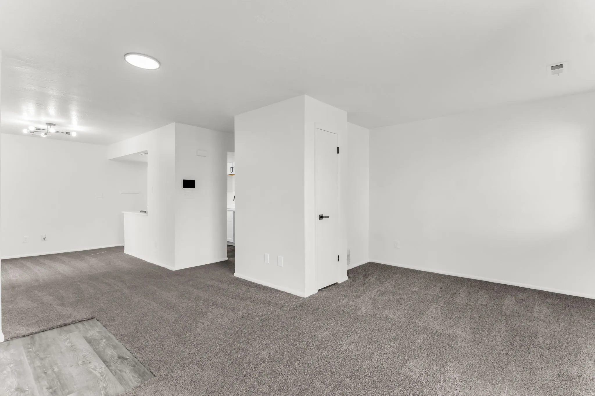 Open concept living area with grey carpeting, white walls, and recessed lighting