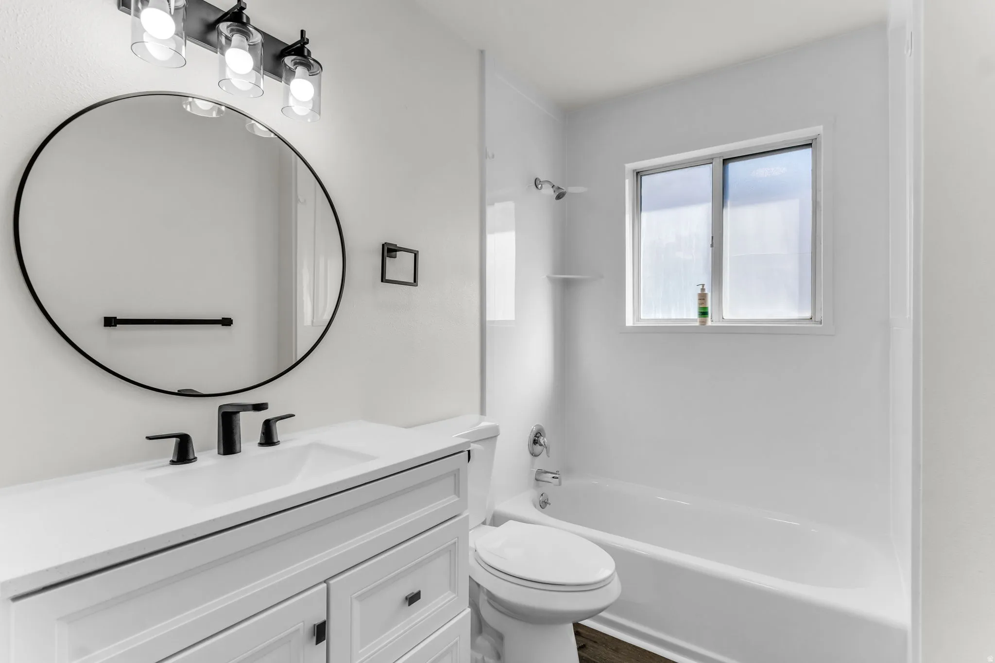 White vanity with matte black fixtures, an oval mirror, and an overhead three-light fixture