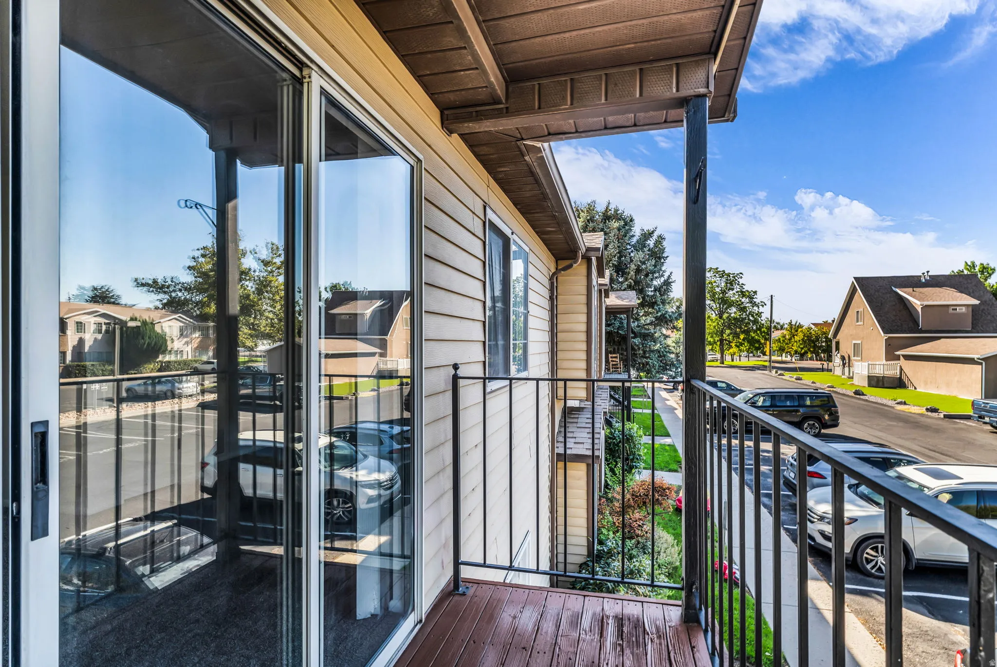 Balcony with wood-finish decking, black metal railing, and sliding glass door