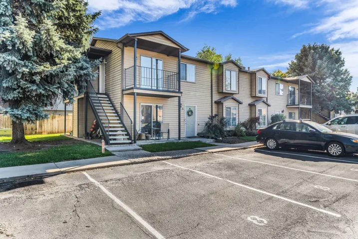Multi-story exterior with horizontal siding, individual balconies, bay windows, and dedicated parking
