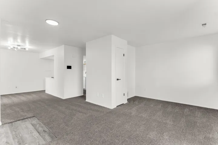 Open concept living area with grey carpeting, white walls, and recessed lighting