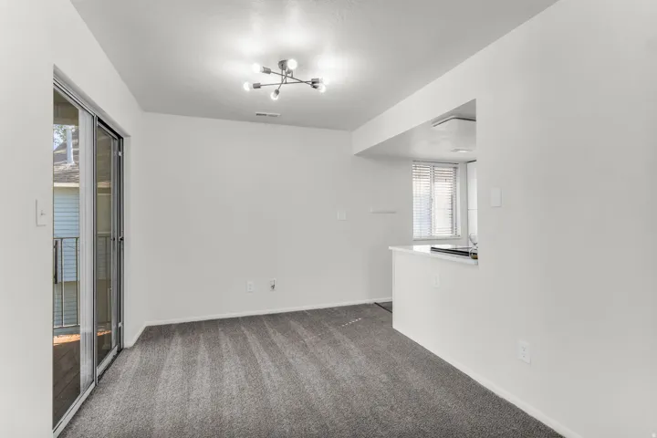 Recessed kitchen pass-through with white countertop, contemporary ceiling light fixture, sliding glass door, and neutral wall paint