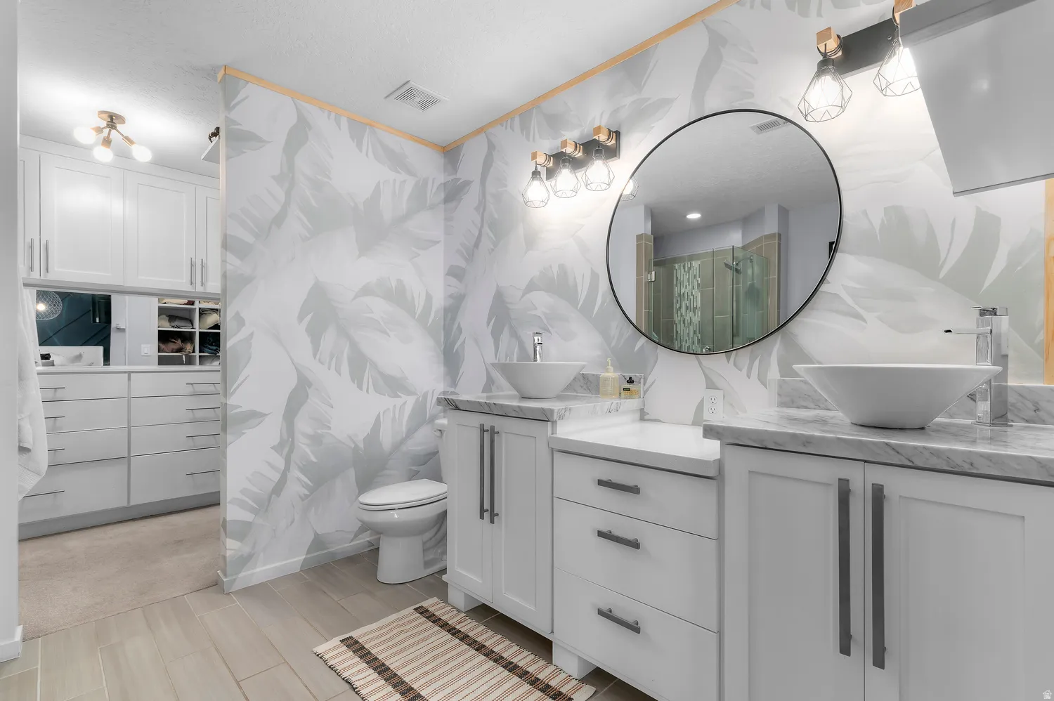 Dual vanity with vessel sinks, marble-finish countertops, and white cabinetry