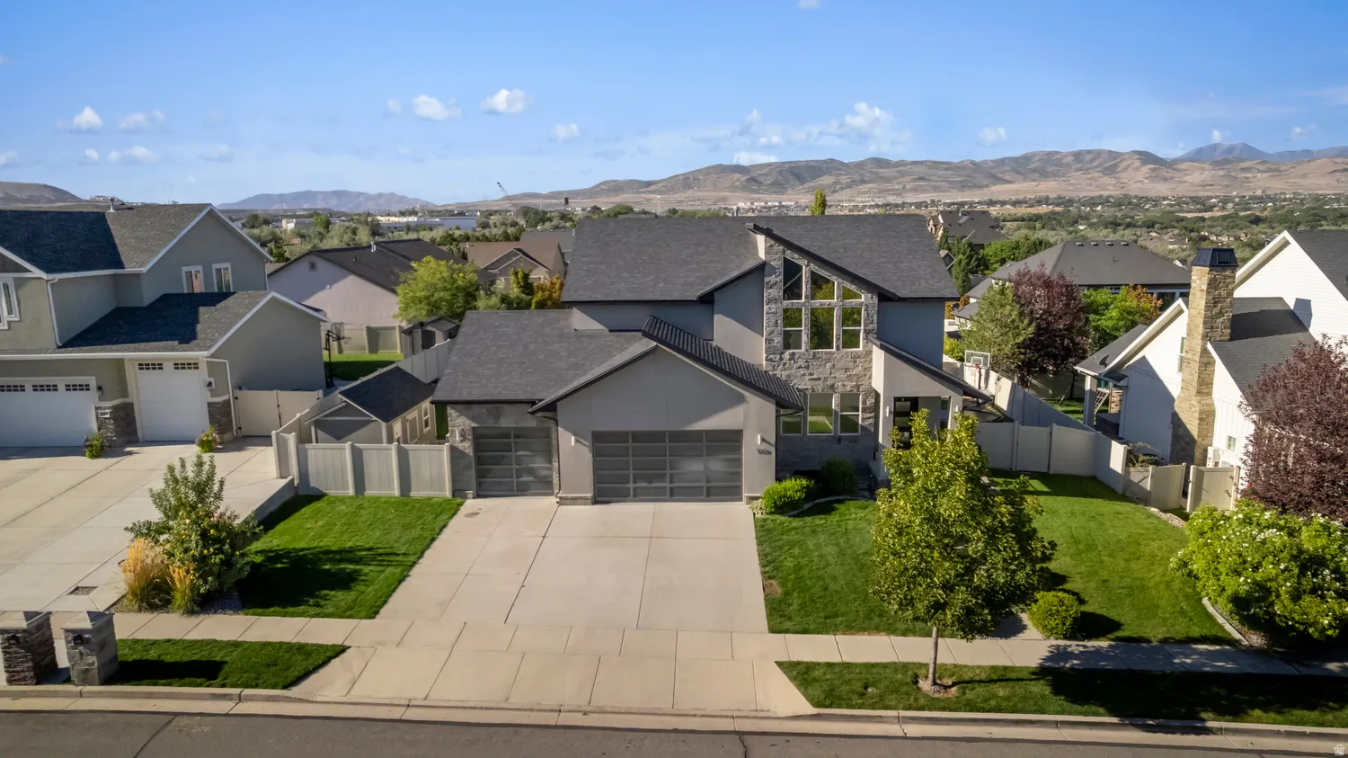 Modern home featuring a stone and stucco exterior, prominent peaked rooflines, and a two-car garage with frosted glass doors