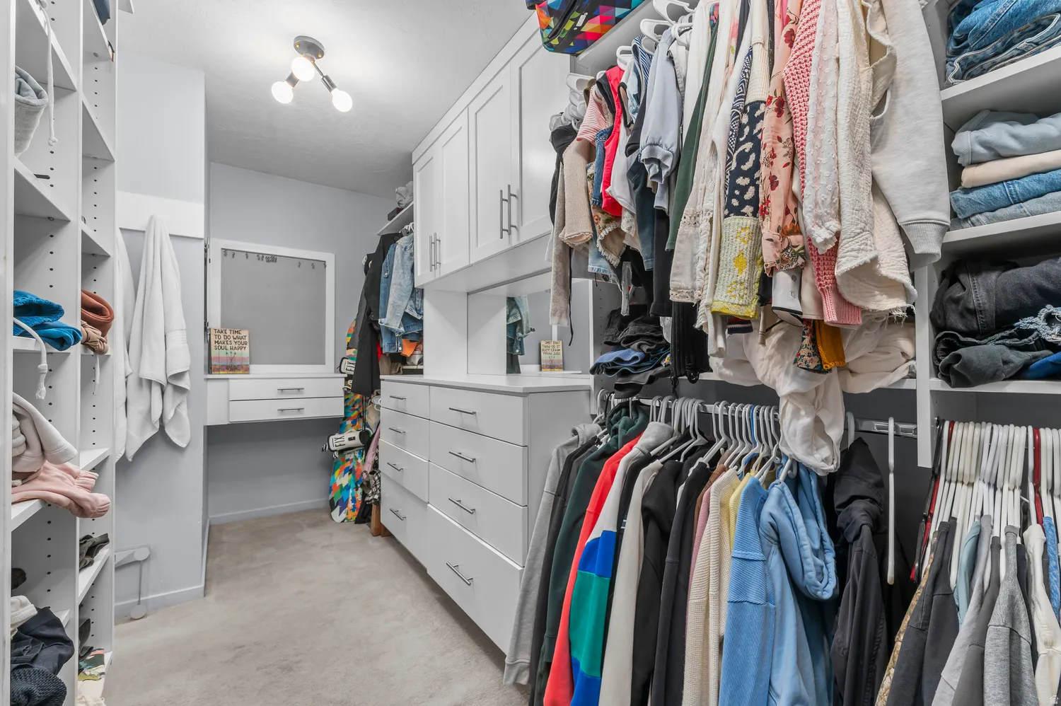 Built-in custom closet system with extensive shelving, drawer storage, cabinetry, and a vanity space