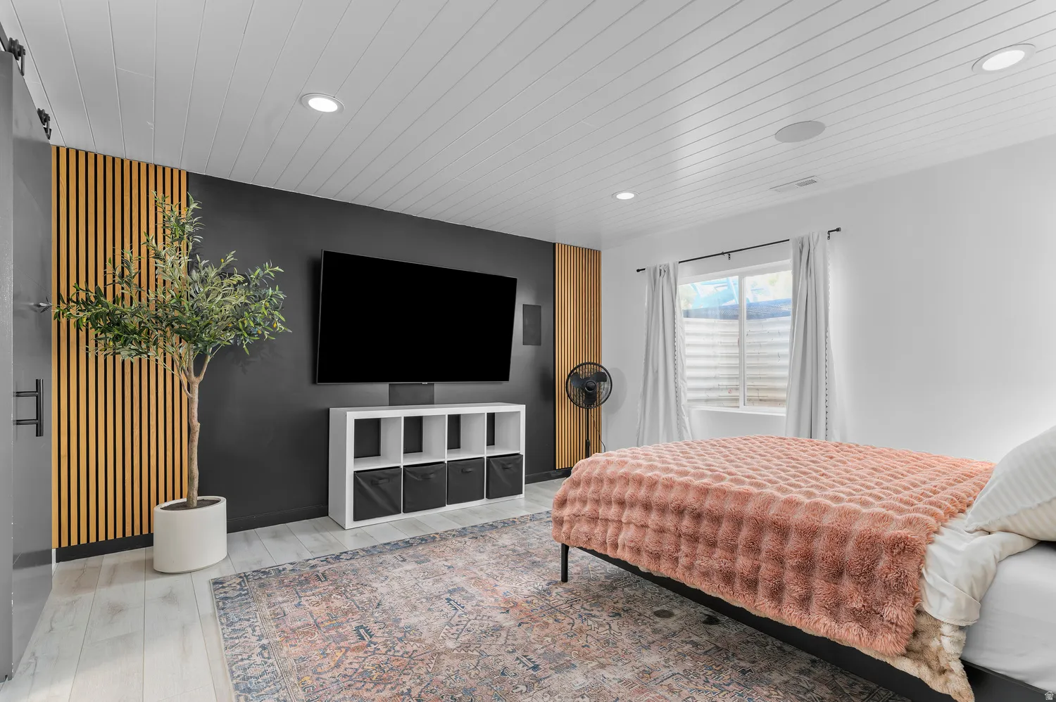 Recessed lighting, wood-finish flooring, accent wall with vertical wood slats, and a barn door with black hardware