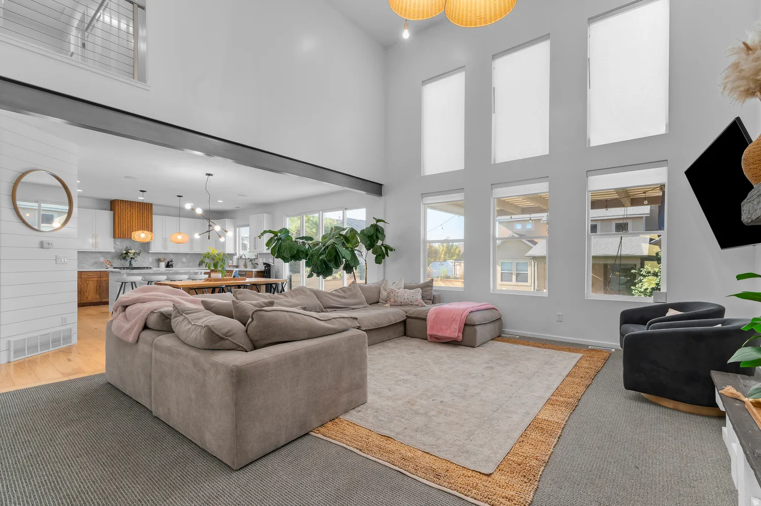Soaring ceilings with upper-level windows, a spacious living area, and an open-concept kitchen with a dining area