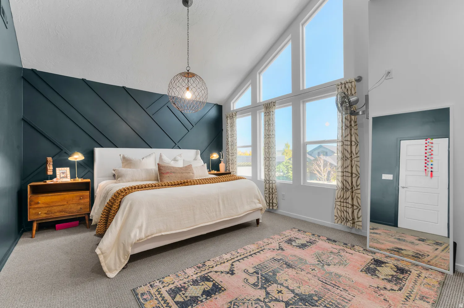 Vaulted ceilings, accent wall with geometric paneling, large windows, recessed lighting, and wall-mounted light fixture