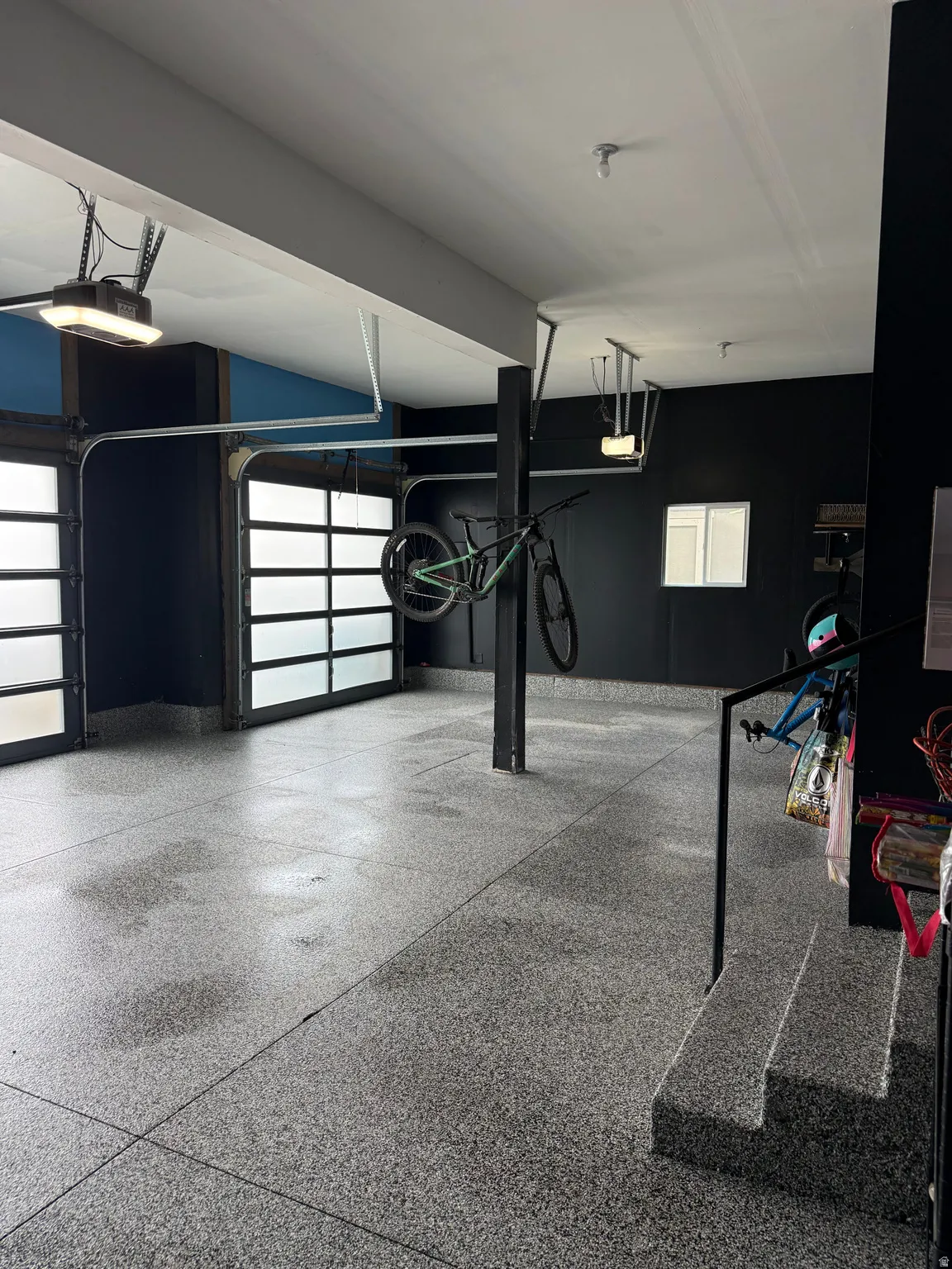 Spacious garage with two frosted-panel garage doors, a window, and durable speckled flooring