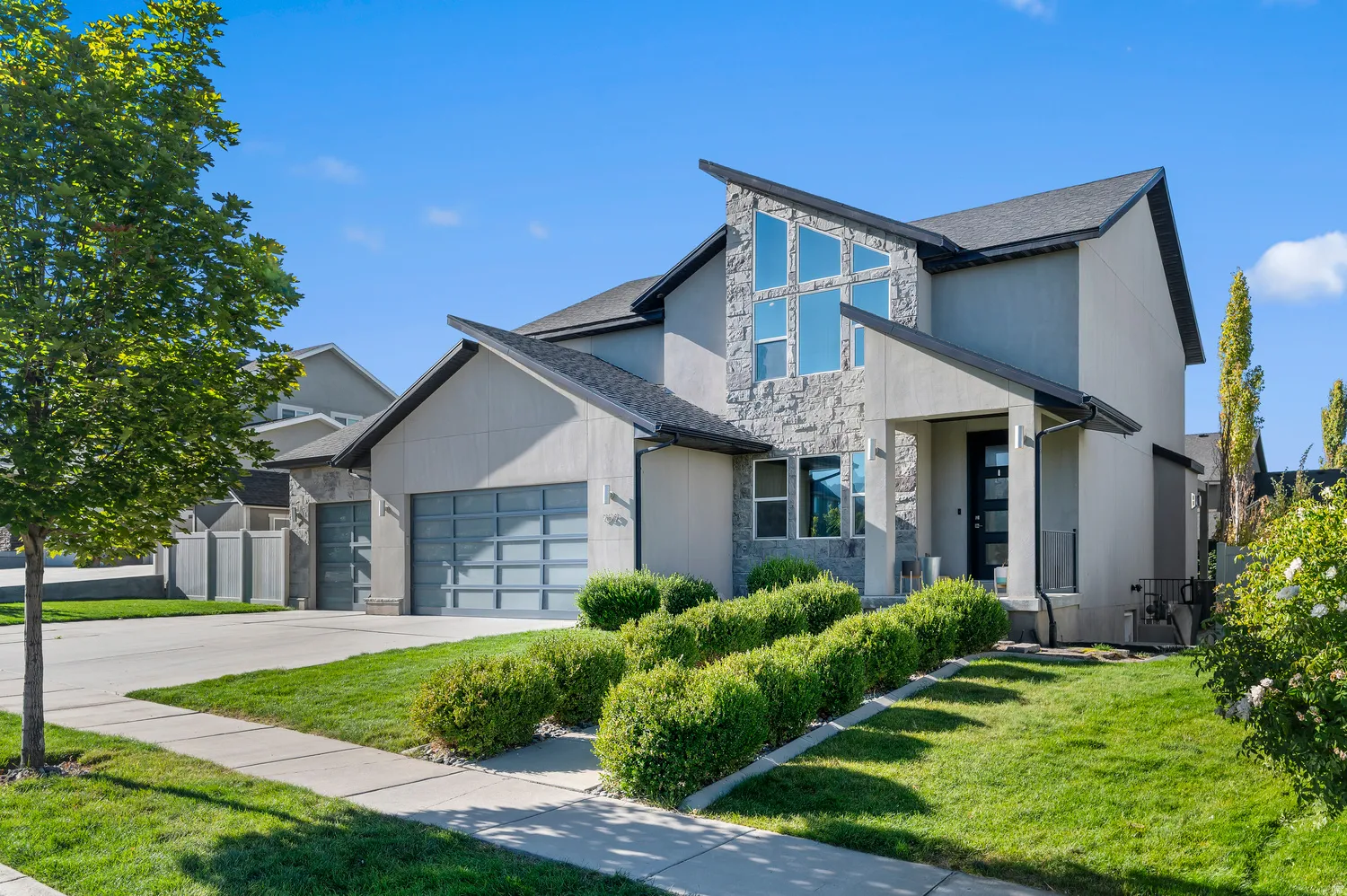 Contemporary stucco exterior with stone accents and a prominent angular roofline