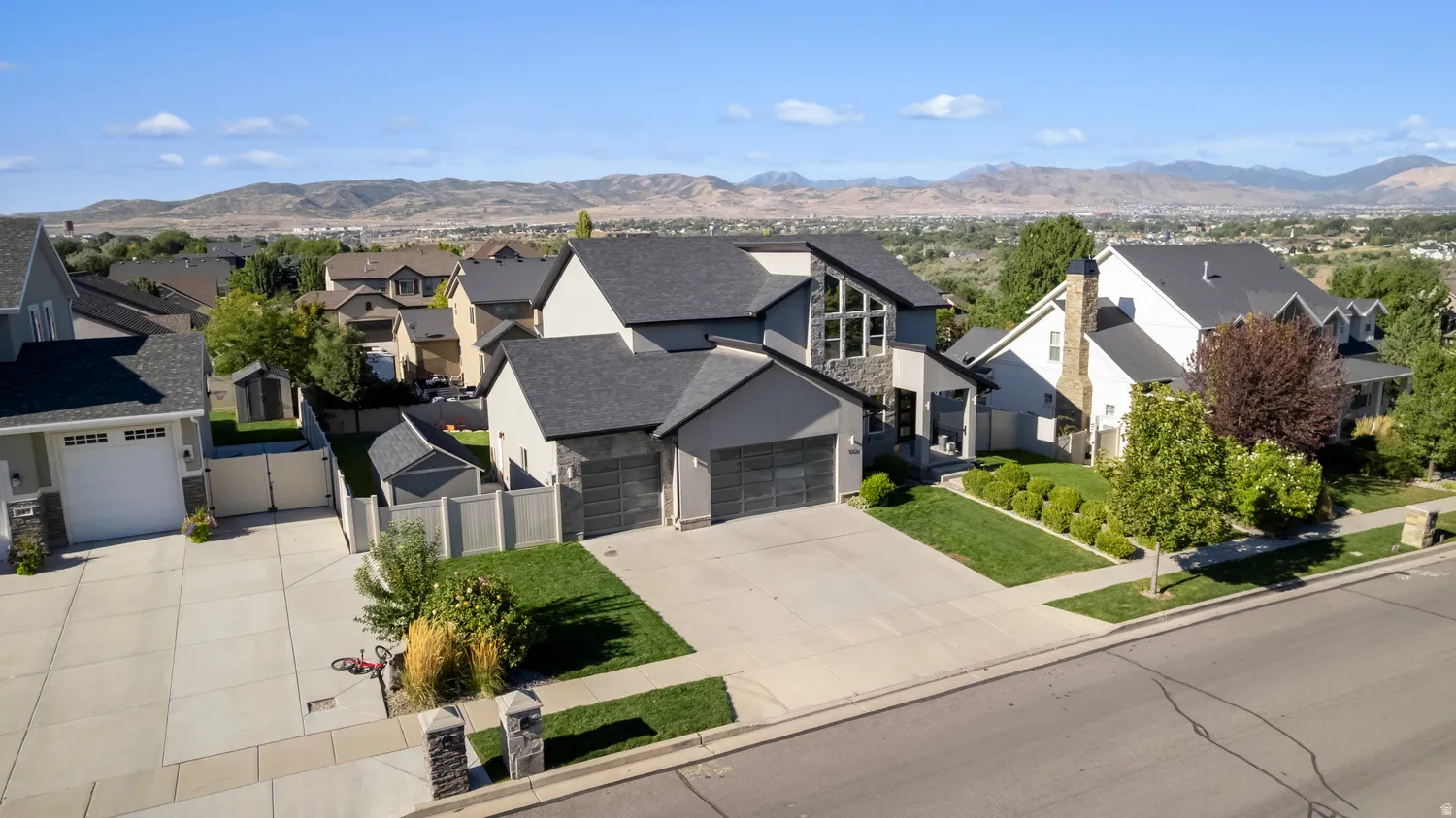 Contemporary exterior with a multi-gabled roofline, stone and stucco facade, a two-car garage, and an additional single-car garage