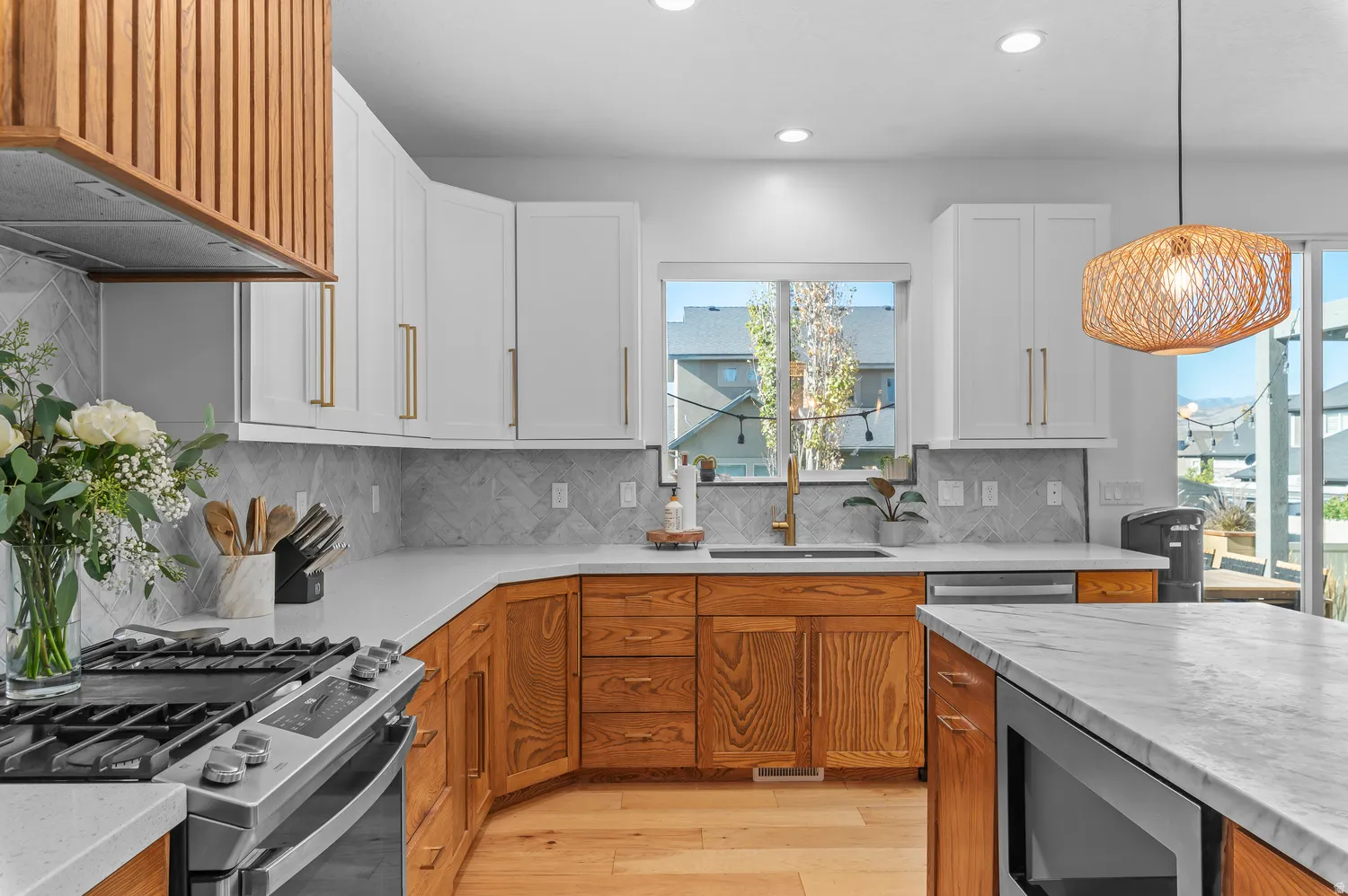 Two-tone cabinetry, herringbone tile backsplash, stainless steel appliances, recessed lighting, and a kitchen island with a built-in microwave